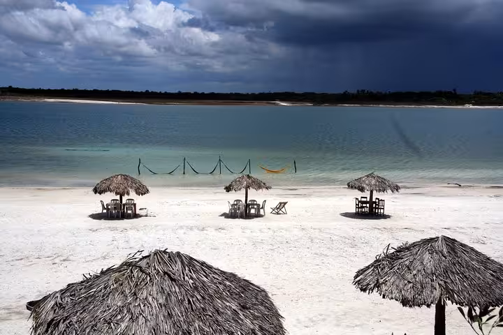 Beach umbrellas and hammocks by a turquoise lagoon in Jericoacoara, ideal stop on a 1-day tour