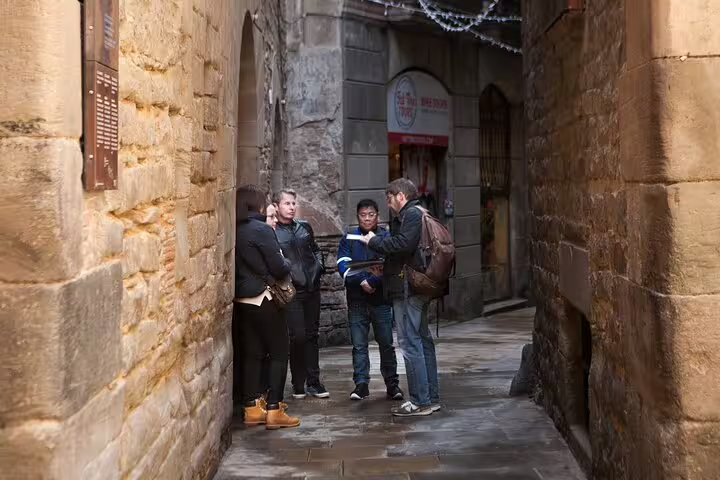 Tourists explore the historic Jewish Quarter, guided through its narrow stone alleys, part of a private religious tour in Barcelona.