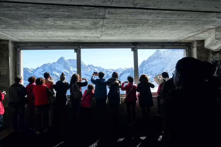 Tourists enjoying panoramic mountain views from the Jungfraujoch observation deck on a private day trip.