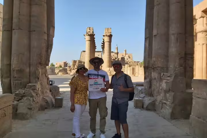 Tourists standing between towering Karnak Temple columns in Luxor on a private full-day Aswan to Luxor car tour