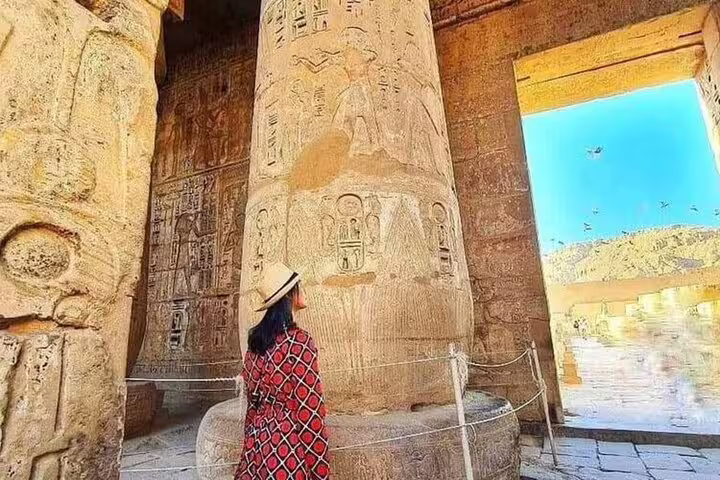 Visitor admiring carved hieroglyphs inside Karnak Temple during a full-day private guided tour from Safaga