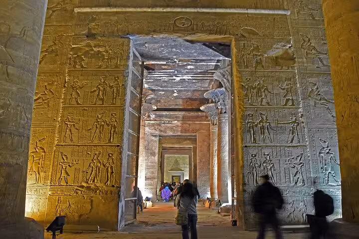 Tourists walking through Karnak Temple carved gateway on Luxor to Abu Simbel overnight Aswan trip