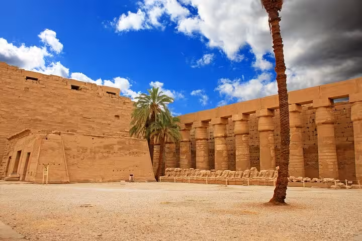 Karnak Temple courtyard in Luxor on Cairo to Luxor flight day trip, with palm trees and towering columns