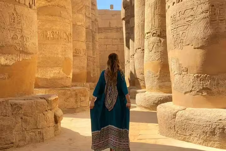 Traveler walking among Karnak Temple columns, Luxor on private overnight Cairo to Luxor tour by flight