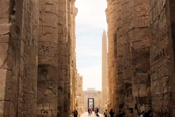 Avenue between massive Karnak Temple walls with obelisk, Luxor on private Cairo to Luxor flight tour