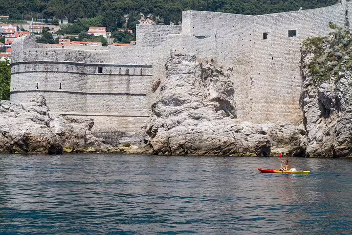 Single kayak near Dubrovnik fortress walls on an Adriatic sunset kayaking and snorkeling tour with water and wine