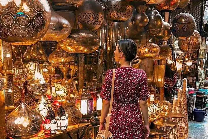 Traveler browsing glowing brass lanterns at Khan El Khalili market on private Cairo day tour from Dahab by flight