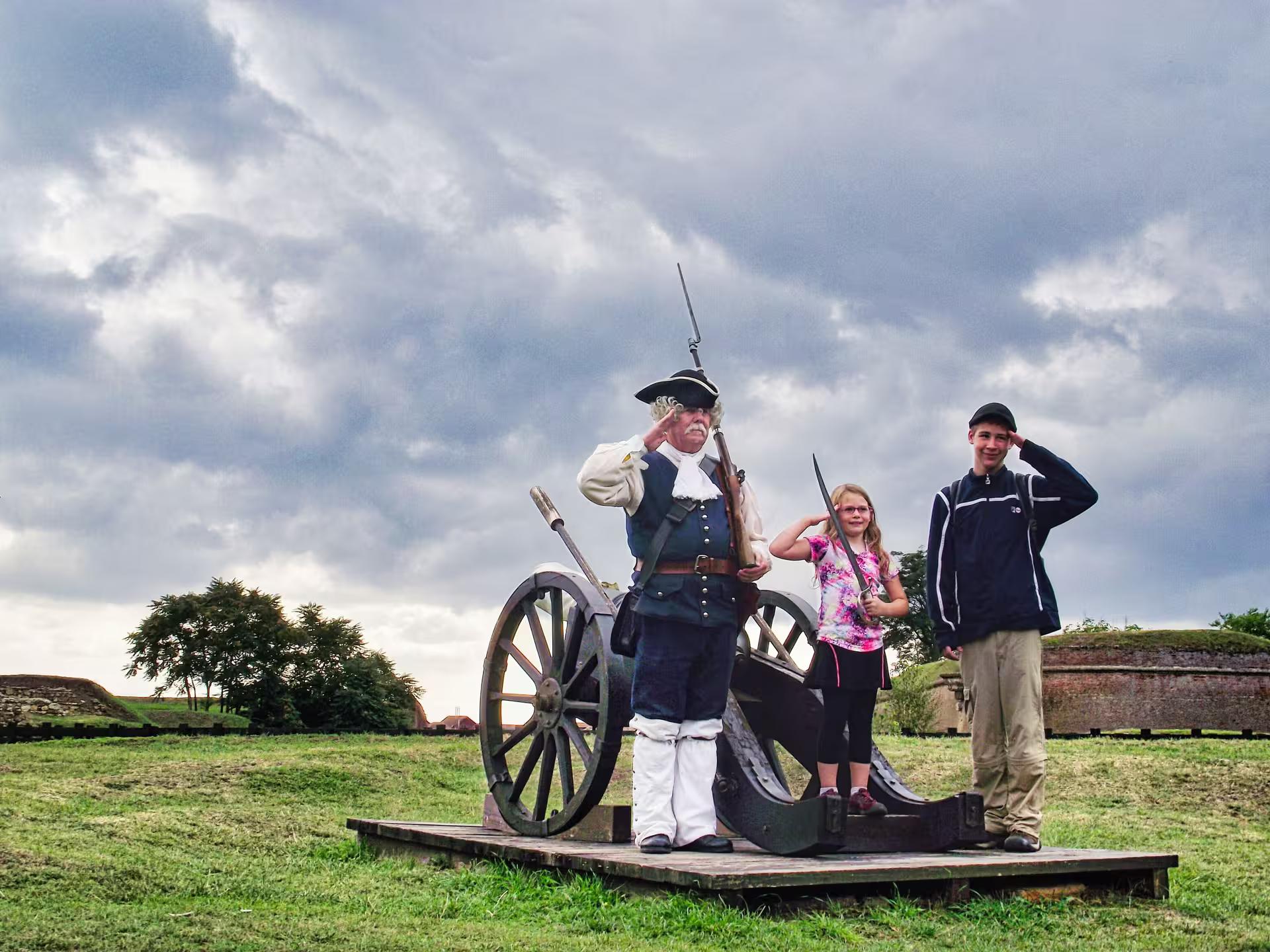 Kids posing with historical soldier reenactor and cannon at Corvin Castle guided tour from Cluj