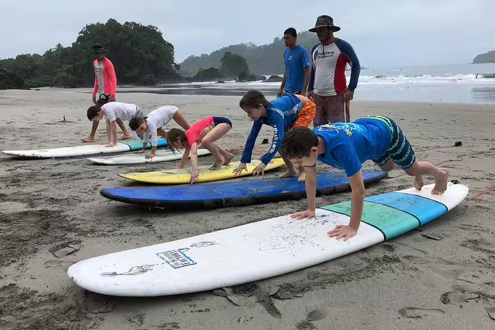 Kids learning to surf with expert instructors on a scenic beach in Manuel Antonio, perfect for family surf lessons.
