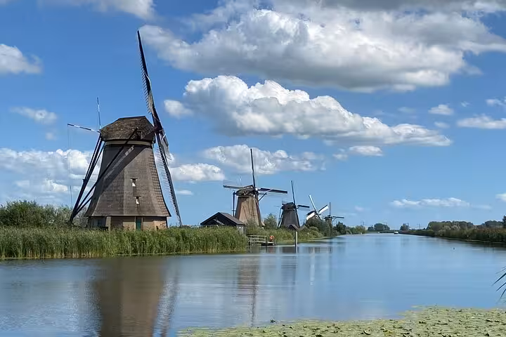 Kinderdijk windmills reflected in canal under blue sky, highlight of private tour from Rotterdam to Delft and The Hague