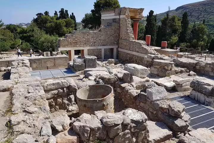 Explore the ancient ruins of Knossos Palace, featuring stunning stone architecture and lush greenery in Crete, Greece.