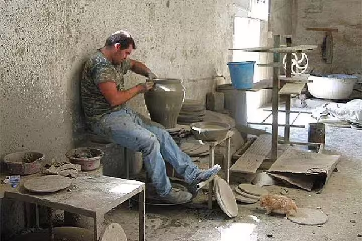 Artisan crafting pottery in a rustic workshop, part of the immersive Knossos Palace pottery experience.