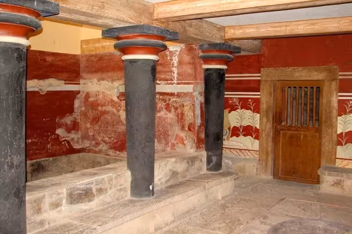 Interior of Knossos Palace with black columns and Minoan fresco walls, stop on Knossos & Heraklion tour from Rethimno