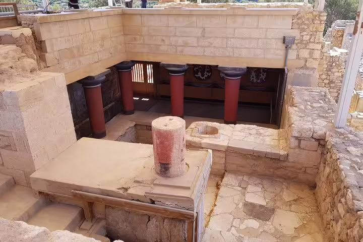 Ancient ruins of Knossos Palace with iconic red columns, offering a glimpse into Minoan civilization on a luxury adventure tour.