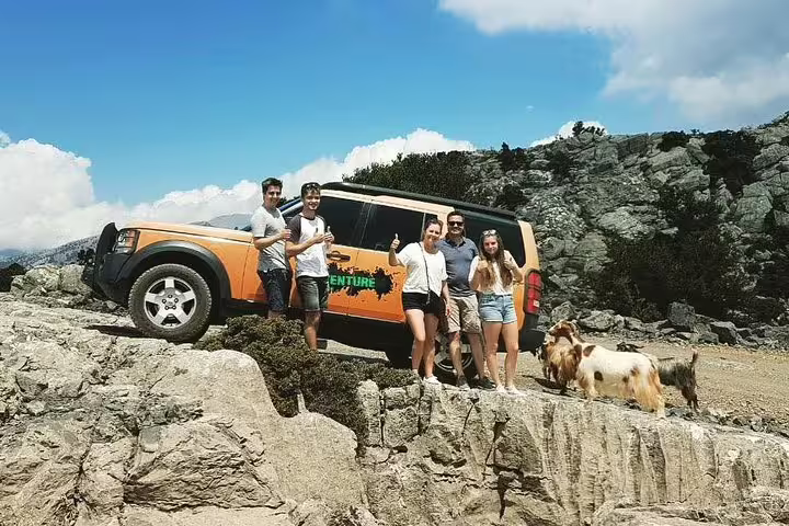 Group enjoying a scenic off-road adventure near Knossos Palace with a rugged SUV and stunning mountain views.