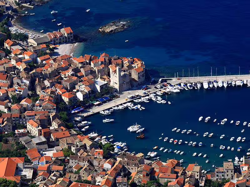 Aerial of Komiza town on Vis Island with marina and stone houses, stop on Vis and Hvar Blue Cave boat tour