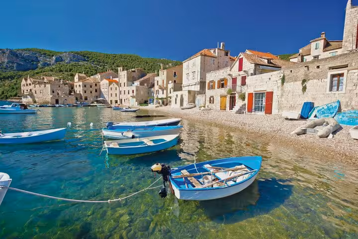Komiza, Vis Island waterfront with small boats in clear Adriatic water on Blue Cave and Hvar speedboat tour