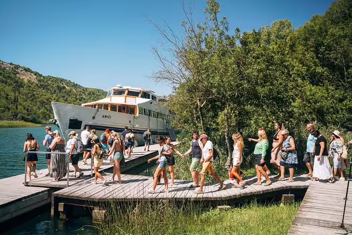 Guests boarding boat cruise at Krka National Park pier for scheduled Krka Waterfalls tour and swimming stop