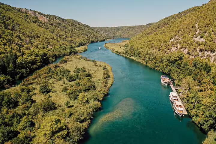 Aerial view of Krka River canyon with boats docked, scenic boat cruise route on Krka Waterfalls tour