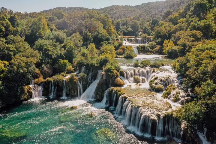 Panoramic Krka Waterfalls cascades and emerald pools on scheduled tour with boat cruise and swim stop