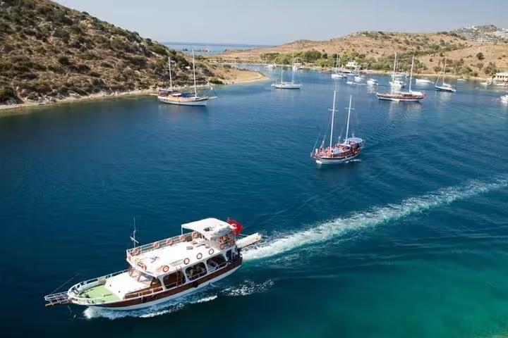 Scenic boat trip from Kusadasi with yachts cruising in clear blue waters surrounded by lush hills.