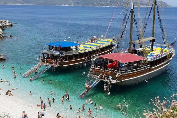 Scenic boat trip along Kusadasi coast with tourists enjoying crystal-clear waters and beach activities.