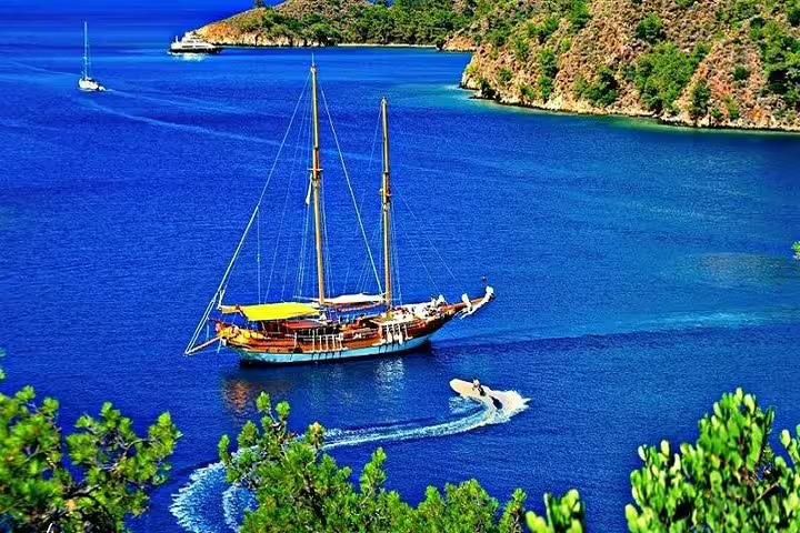 Scenic view of a sailboat cruising in deep blue waters surrounded by lush hills on a Kusadasi boat trip adventure.