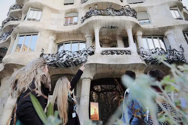 Guide pointing out Gaudí details on La Pedrera’s wavy balconies during a morning Barcelona tour with optional Casa Batlló ticket