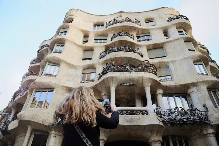 Traveler taking a morning photo of Gaudí’s La Pedrera façade on a guided tour in Barcelona with optional Casa Batlló visit