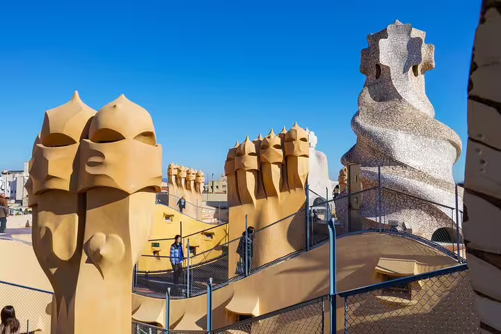 Tourists explore La Pedrera rooftop with its sculptural chimneys and spiral tower on a guided Gaudí morning tour in central Barcelona