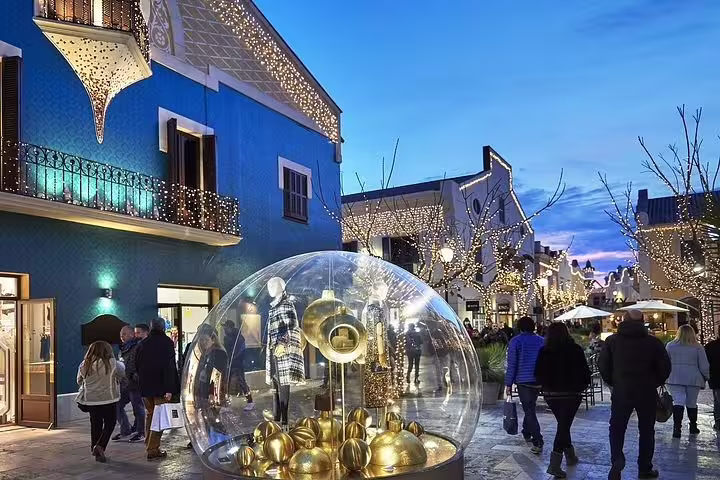 Evening ambiance at La Roca Village with festive lights and a unique shop display, ideal for a magical shopping tour.