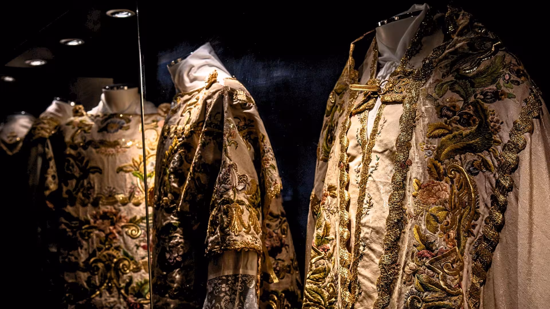 Intricately embroidered traditional garments displayed in a Laconi museum, showcasing Sardinian cultural heritage.