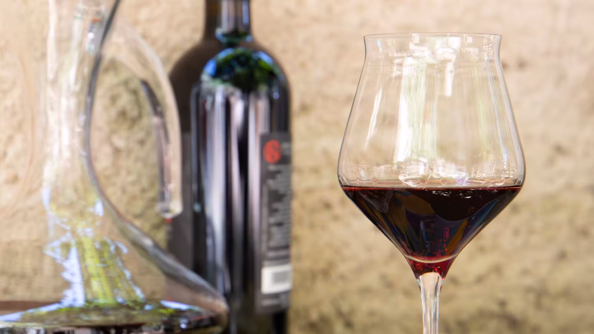 Close-up of a red wine glass and bottle at a Laconi winery, perfect for savoring rich flavors during wine tasting.