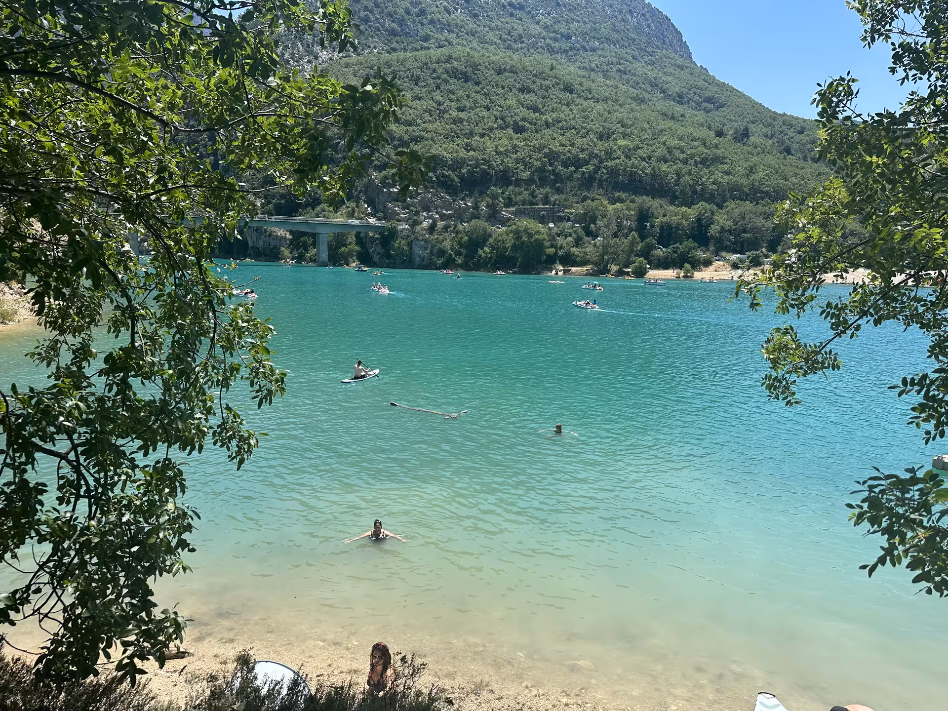 Lake Sainte-Croix beach view with swimmers and paddleboards under mountain cliffs, perfect add-on to lavender tour