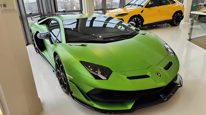 Green Lamborghini supercar on display at the Lamborghini Museum near Bologna, Italy, with Urus in background