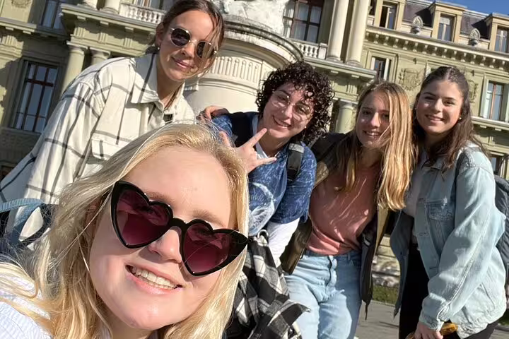 Friends pose outside Palais de Rumine during a Lausanne city center scavenger hunt and sights tour