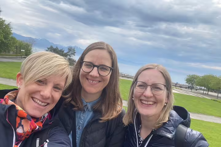 Smiling friends at Lausanne lakeside park on a city center scavenger hunt and sights self-guided tour