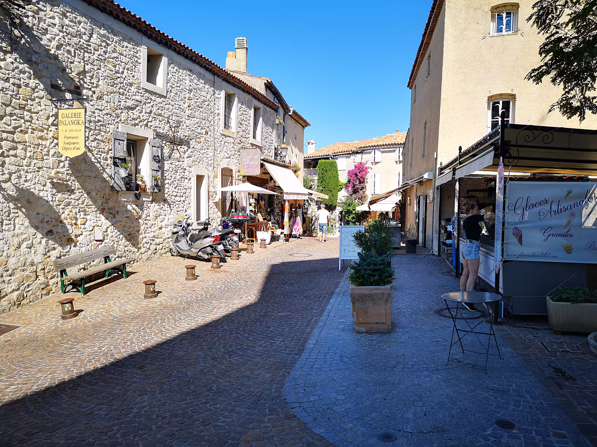 Sunny cobblestone street in Le Castellet village with artisan shops, featured on a private Provence day trip