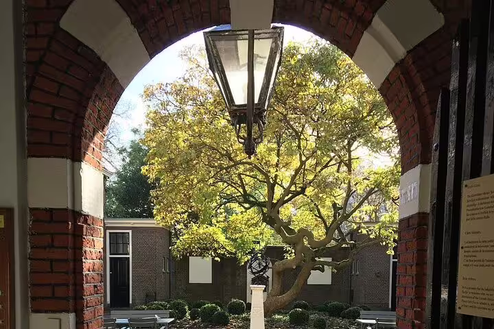 Brick archway framing a leafy courtyard in Leiden, highlight on a half-day private guided walking tour