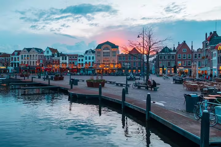 Sunset over Leiden harbor with waterfront cafes and historic Dutch houses, ideal stop on a self-guided GPS tour
