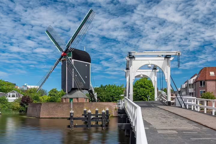 Leiden windmill beside a white drawbridge on a canal, scenic landmark on the Discover Leiden self-guided GPS tour