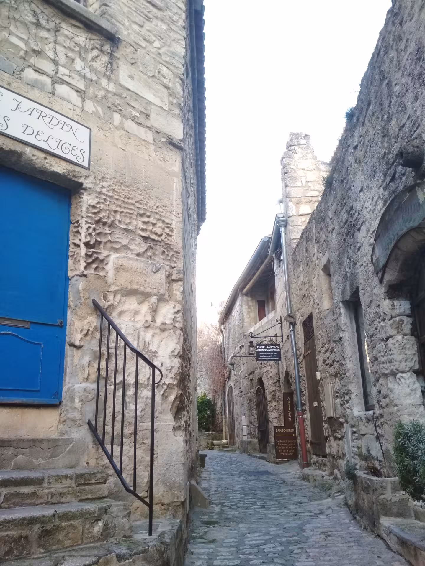 Cobblestone lane with stone houses and blue door in Les Baux-de-Provence, Provence village walking tour