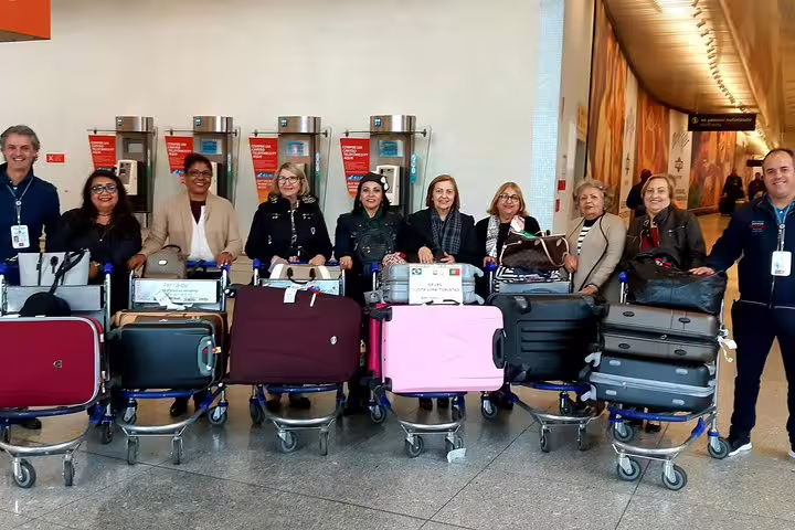 Group with luggage trolleys at Lisbon Airport, enjoying seamless transfer to Lisbon accommodations.