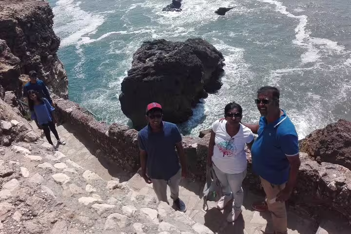 Tourists enjoying scenic coastal views on a heritage tour near Lisbon, Portugal, showcasing stunning rock formations and ocean waves.