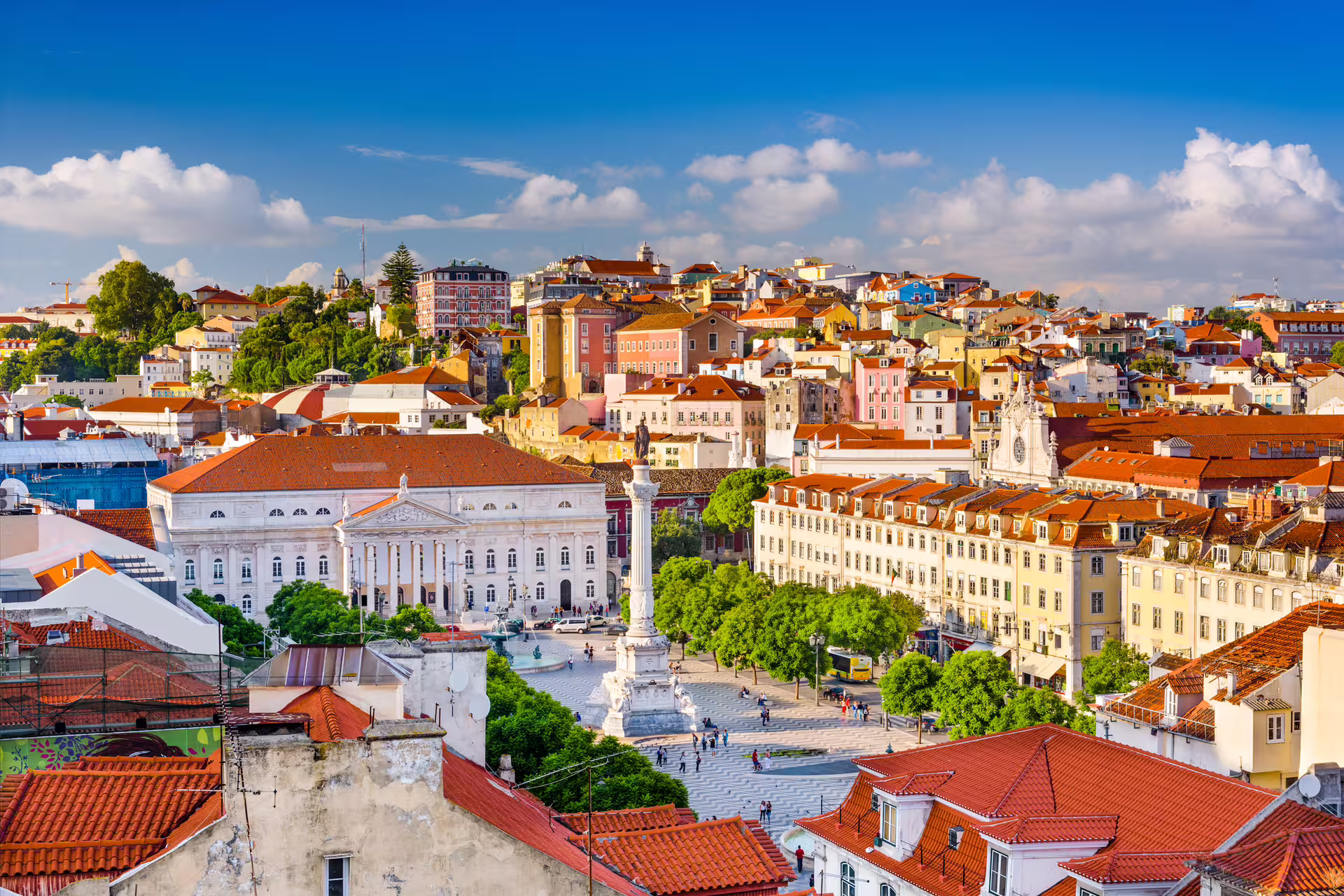 Panoramic view of Lisbon's vibrant historic district, showcasing colorful architecture and bustling city life under a clear sky.