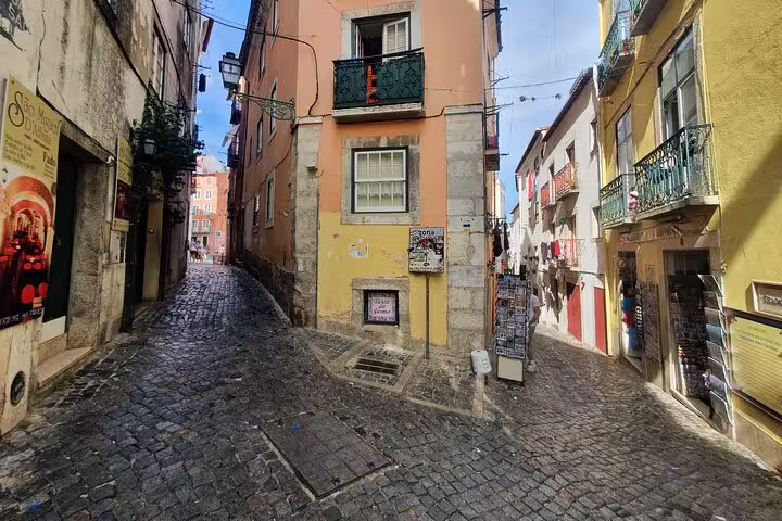 Charming cobblestone street in Lisbon's Old Town with colorful buildings, perfect for exploring on a private full-day tour.