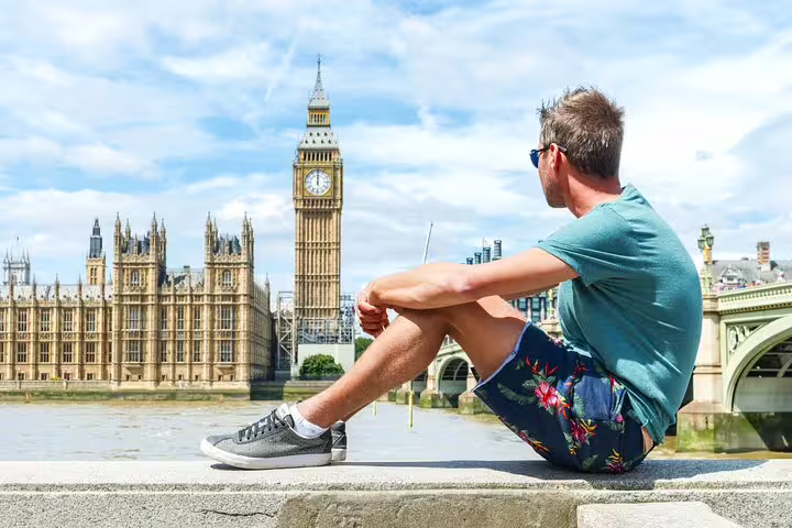 Traveler enjoying a sunny day by the Thames with views of Big Ben and the Houses of Parliament on a London private tour.