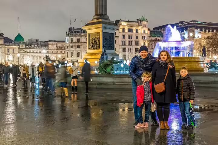 Family enjoying a vibrant evening at Trafalgar Square fountain during a London full-day private tour with Westminster Abbey tickets.