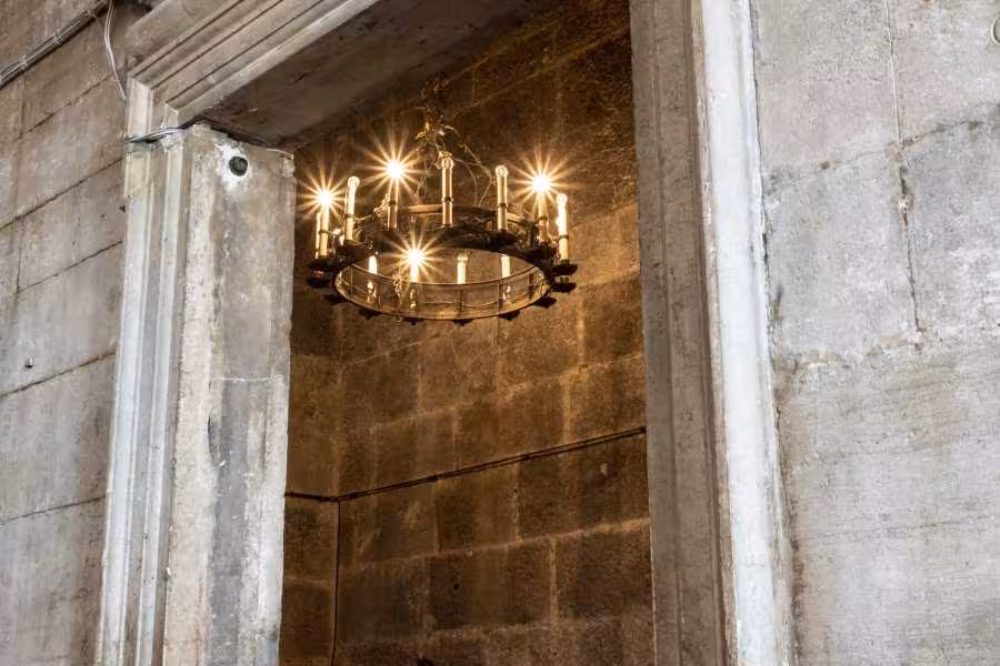 Dimly lit ancient cell with rustic chandelier in Lords of The Night Prison Palace tour.