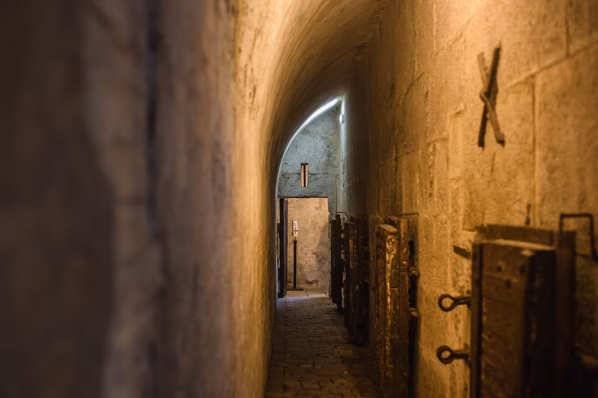 Dimly lit stone corridor in Lords of The Night Prison Palace, showcasing eerie cells and historic atmosphere.